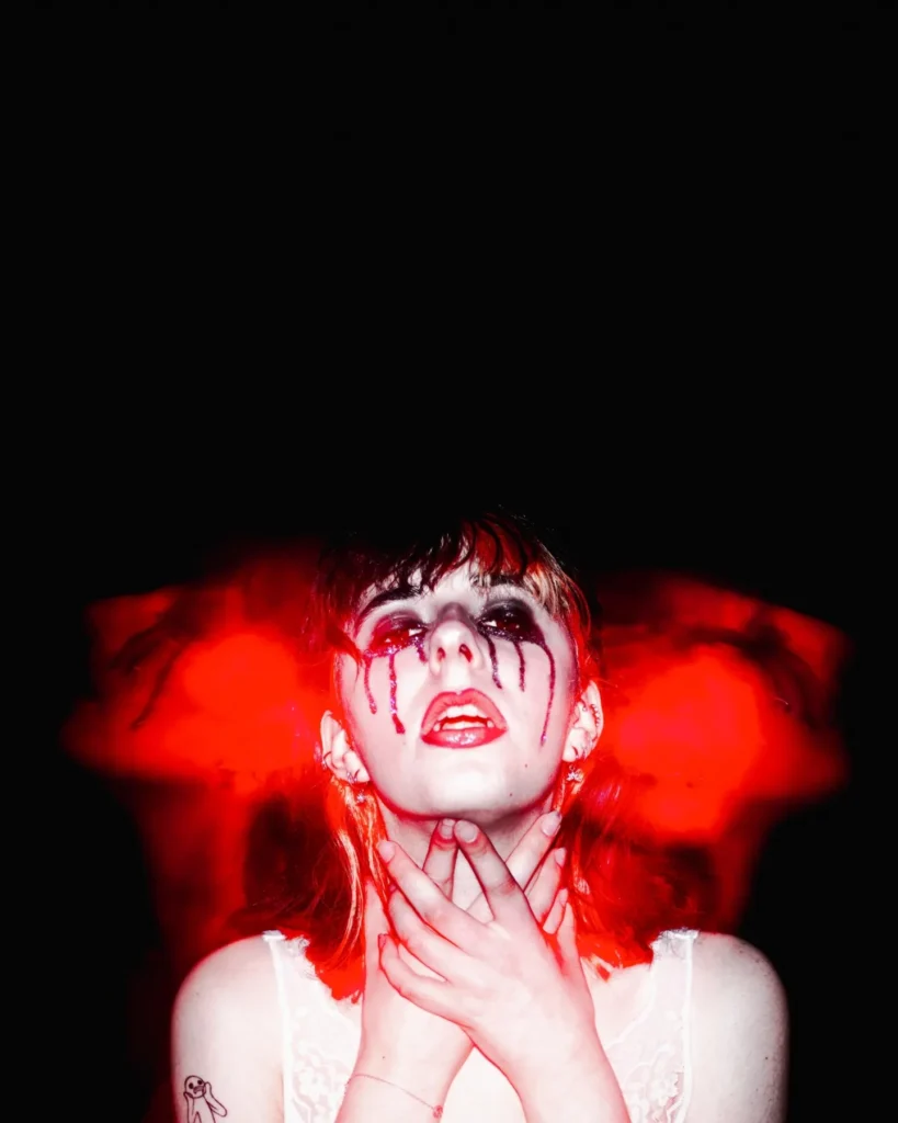 Portrait expressif d’une femme aux larmes sombres sur fond noir avec effet de lumière rouge en mouvement, signé Lo_garithme.