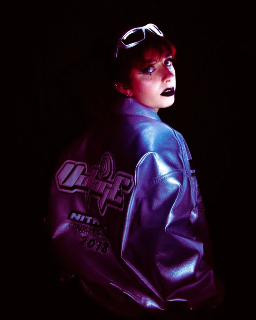 Femme avec un blazer métallisé se retournant dans une lumière violette, ambiance artistique avec effet visuel trouble