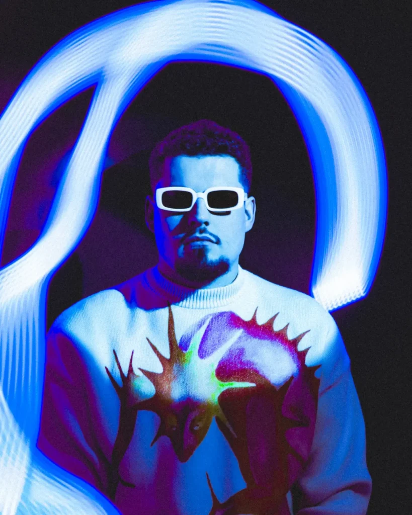 Portrait artistique d’un homme en lunettes blanches éclairé par une traînée lumineuse bleue sur fond noir, réalisé par le photographe Lo_garithme.